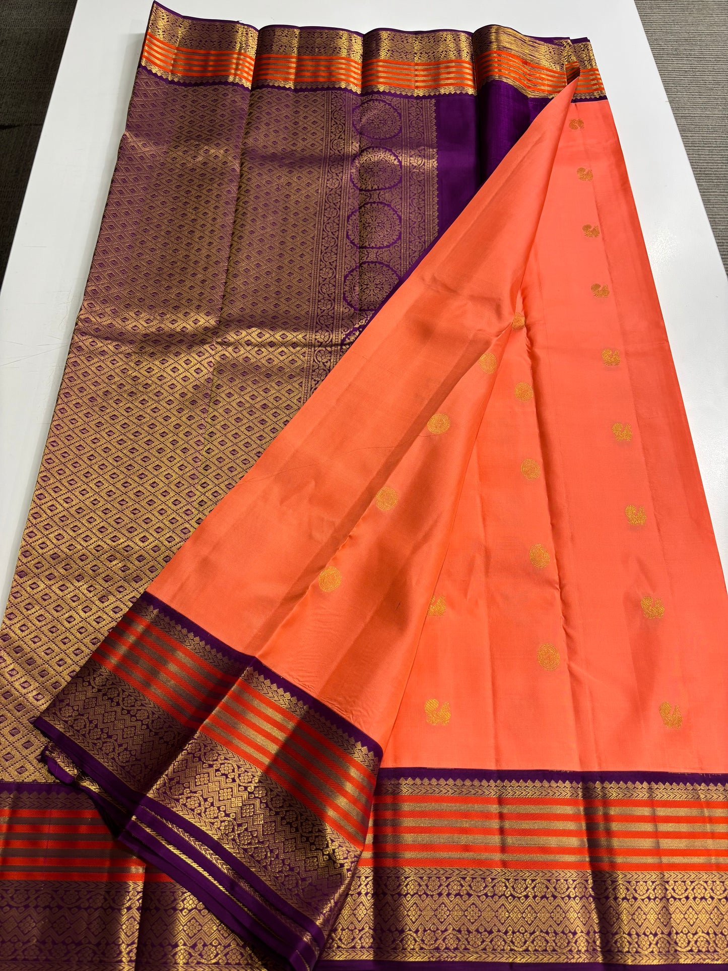 Elegant Peach‑Orange Silk Saree Featuring Classic Purple Highlights & Traditional Zari Accents